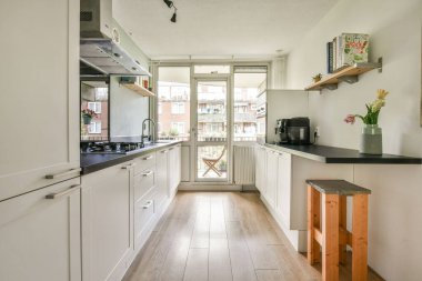 Gündüz vakti modern dairede bulunan modern dolap ve aletlerle aydınlık mutfağın içi.