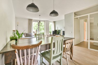 Modern apartmandaki dekorasyonlu ve televizyonlu, rahat koltuğun yanına yerleştirilmiş eski püskü ahşap masa.