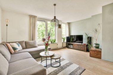 Modern apartmandaki dekorasyonlu ve televizyonlu, rahat koltuğun yanına yerleştirilmiş eski püskü ahşap masa.