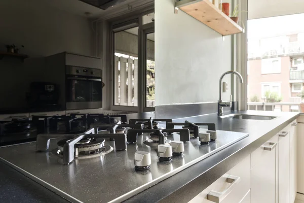 Interior of light kitchen with modern cupboards and appliances located in modern flat at daytime