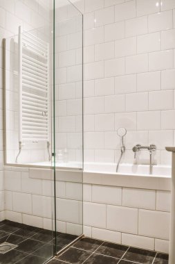 Aynalı lavabo ve temiz küvet modern banyoda cam kapılı ve beyaz fayanslı duvarları olan duş kutusunun yanında.