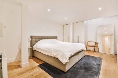 Yatak odasının iç tasarımı, yatak odası ve ahşap gardırop modern dairenin penceresinin kenarına yerleştirilmiş.