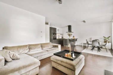 Günümüz minimalist tasarımı. Hafif stüdyo dairesinin ahşap masası ve oturma odası ile beyaz duvarları ve parke zemini arasında yemek masası ve sandalyeleri var.