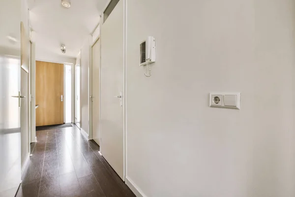 Interior of modern flat in minimal style with narrow empty corridor illuminated by lamps