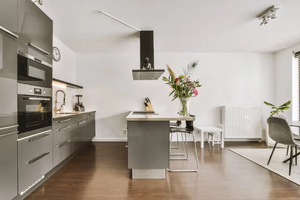 オープンキッチンと白い壁と寄木細工の床とリビングルームの間のダイニングゾーンで木製のテーブルと椅子と光スタジオアパートの現代的なミニマリストスタイルのインテリアデザイン — ストック写真