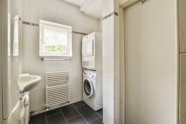 Çağdaş dairenin küçük fayanslı banyosunda lavabo ve duş arasında bulunan sifon tuvaleti