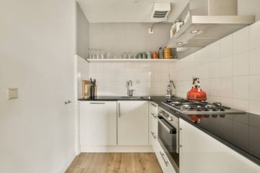 Gündüz vakti modern bir dairede yemek odasının yakınında modern dolaplar ve aletlerle donatılmış aydınlık mutfağın içi.