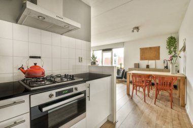 Gündüz vakti modern bir dairede yemek odasının yakınında modern dolaplar ve aletlerle donatılmış aydınlık mutfağın içi.