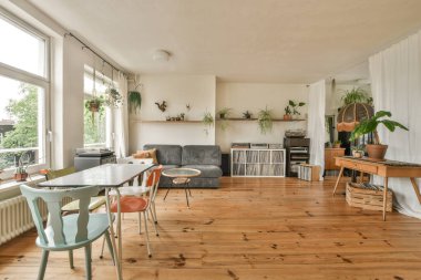 Çağdaş dairenin geniş odasındaki dinlenme odası ve mutfağın yanındaki sandalyeli masa.