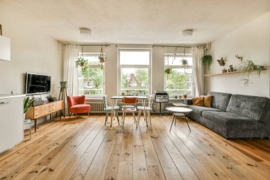 Çağdaş dairenin geniş odasındaki dinlenme odası ve mutfağın yanındaki sandalyeli masa.