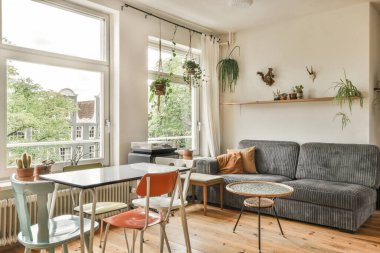 Çağdaş dairenin geniş odasındaki dinlenme odası ve mutfağın yanındaki sandalyeli masa.