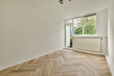 Evdeki boş ışık odasında, beyaz duvardaki plastik pencere ve radyatör.