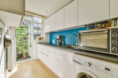 Minimalist stil mutfak, basit dolaplar ve aydınlık dairede modern aletler.