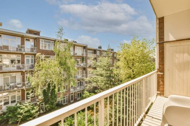 Panoramic view of brick buildings with parking and trees from small balcony