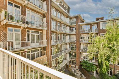 Panoramic view of brick buildings with parking and trees from small balcony