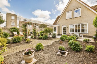 Oturma alanı ve ahşap çitlerin yanındaki küçük bahçesi olan düzgün asfaltlı bir avlu.