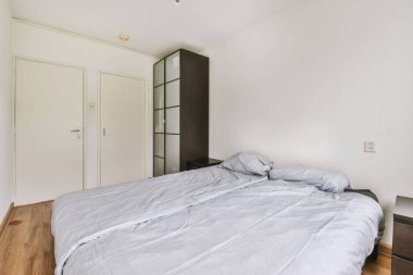 Yatak odasının iç tasarımı, yatak odası ve ahşap gardırop modern dairenin penceresinin kenarına yerleştirilmiş.