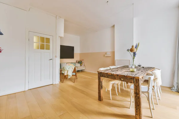 开放式厨房与有白色墙壁和地板的客厅之间设有木制餐桌和椅子的轻便演播室公寓的当代简约风格室内设计 — 图库照片