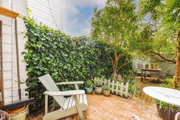 Oturma alanı ve ahşap çitlerin yanındaki küçük bahçesi olan düzgün asfaltlı bir avlu.