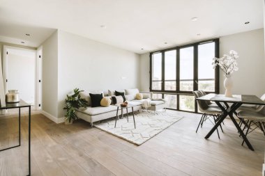 Mutfağın yakınındaki açık oturma odasındaki şöminenin yanındaki zarif avizenin altında yumuşak yastıklı büyük bir kanepe.