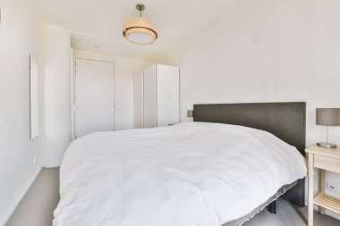 Yatak odasının iç tasarımı, yatak odası ve ahşap gardırop modern dairenin penceresinin kenarına yerleştirilmiş.