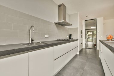 Çağdaş dairenin geniş odasındaki dinlenme odası ve mutfağın yakınındaki sandalyeli ve çiçekli masa.