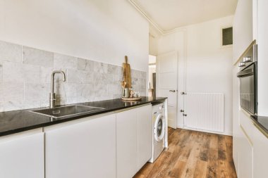 Minimalist tarzı beyaz mobilyalı, lavabolu ve sobalı bir ev mutfağı.