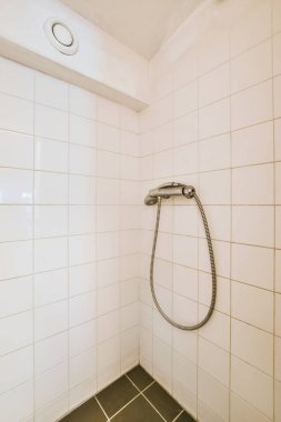 Duş muslukları cam bölmenin yanındaki fayanslı duvara bağlı ve evdeki tuvaletteki süs pervazı.