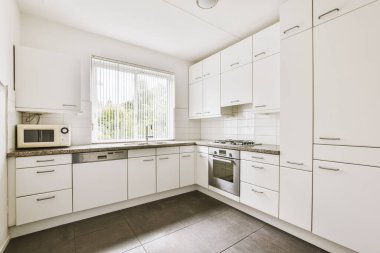 Minimalist tarzı beyaz mobilyalı, lavabolu ve sobalı bir ev mutfağı.