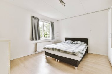 Yatak odasının iç tasarımı, yatak odası ve ahşap gardırop modern dairenin penceresinin kenarına yerleştirilmiş.