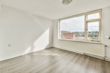 Büyük pencereli ve ahşap parke zeminli boş beyaz odanın içi.