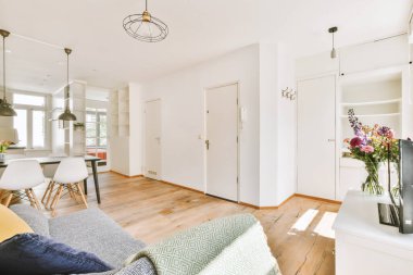 Modern apartmandaki dekorasyonlu ve televizyonlu, rahat koltuğun yanına yerleştirilmiş eski püskü ahşap masa.