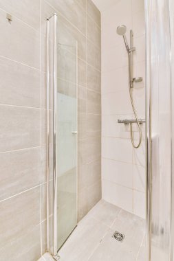 Duş muslukları cam bölmenin yanındaki fayanslı duvara bağlı ve evdeki tuvaletteki süs pervazı.