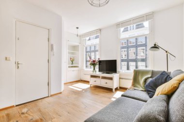 Modern apartmandaki dekorasyonlu ve televizyonlu, rahat koltuğun yanına yerleştirilmiş eski püskü ahşap masa.