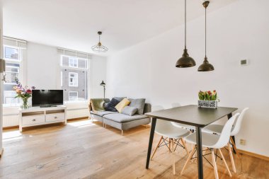 Modern apartmandaki dekorasyonlu ve televizyonlu, rahat koltuğun yanına yerleştirilmiş eski püskü ahşap masa.