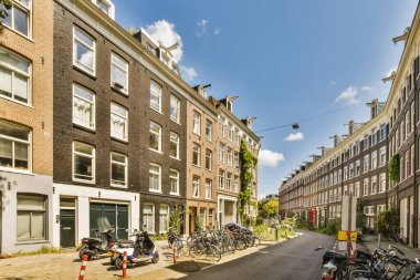 Arabaları, ağaçları ve fenerleri olan boş bir kaldırımdan panorama manzaralı evler.