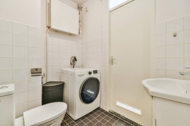 Lavabo ve aynalı dolap kapının yanındaki fayanslı duvara ve modern tuvaletteki kurutma tezgahına bağlı.