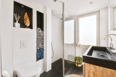 Çağdaş dairenin küçük fayanslı banyosunda lavabo ve duş arasında bulunan sifon tuvaleti