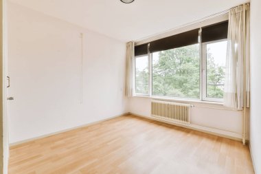 Evdeki boş ışık odasında, beyaz duvardaki plastik pencere ve radyatör.