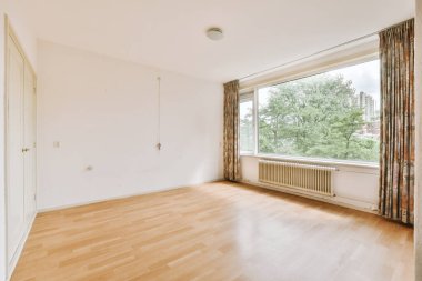 Evdeki boş ışık odasında, beyaz duvardaki plastik pencere ve radyatör.