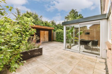 Oturma alanı ve ahşap çitlerin yanındaki küçük bahçesi olan düzgün asfaltlı bir avlu.