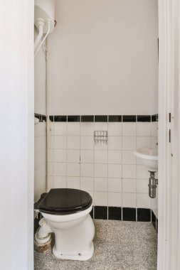 Lavabolu ve duvarlı, beyaz duvarlı ve kareli tuvaletli dar bir tuvalet.