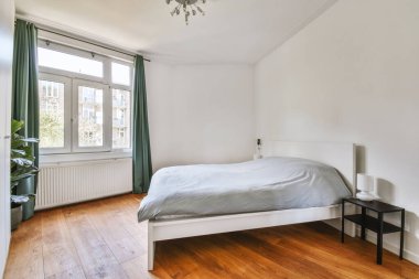 Yatak odasının iç tasarımı, yatak odası ve ahşap gardırop modern dairenin penceresinin kenarına yerleştirilmiş.