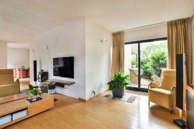 Çağdaş dairenin geniş odasındaki dinlenme odası ve mutfağın yakınındaki sandalyeli ve çiçekli masa.