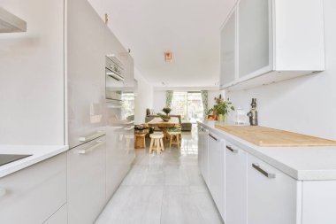 Günümüz minimalist tasarımı. Hafif stüdyo dairesinin ahşap masası ve oturma odası ile beyaz duvarları ve parke zemini arasında yemek masası ve sandalyeleri var.
