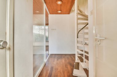 Beyaz sarmal merdiven parke zemin ve beyaz duvarlarla çağdaş evin seviyelerini bağlıyor.