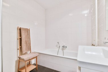 Aynalı lavabo ve temiz küvet modern banyoda cam kapılı ve beyaz fayanslı duvarları olan duş kutusunun yanında.