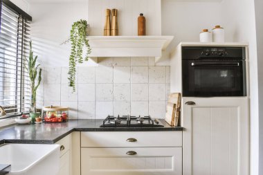 Minimalist tarzı beyaz mobilyalı, lavabolu ve sobalı bir ev mutfağı.