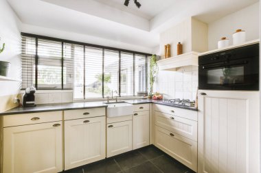 Minimalist tarzı beyaz mobilyalı, lavabolu ve sobalı bir ev mutfağı.