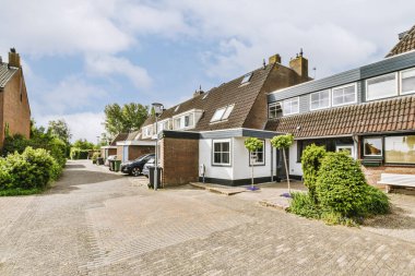 Arabaları, ağaçları ve fenerleri olan boş bir kaldırımdan panorama manzaralı evler.